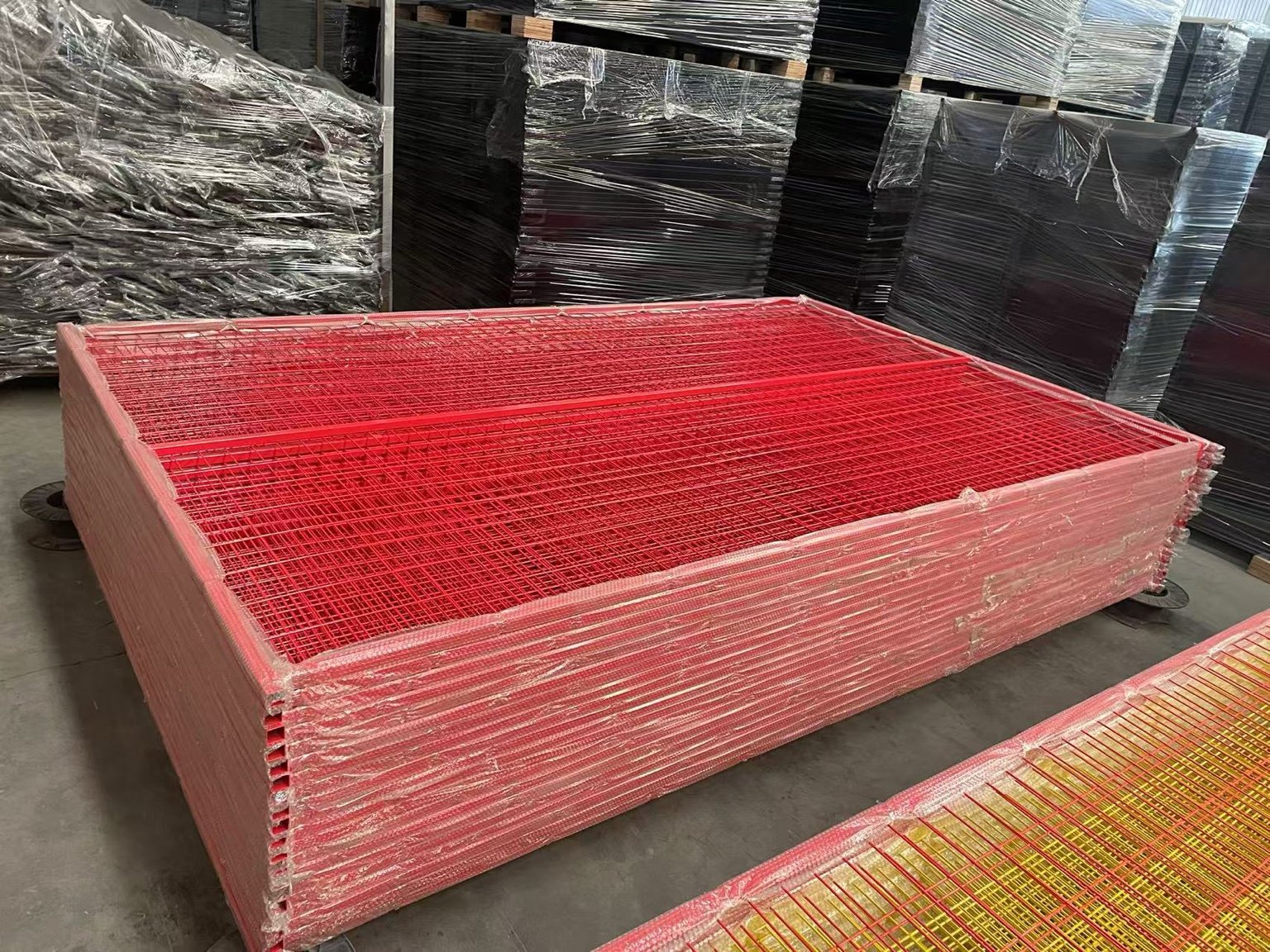 Red and yellow temporary fencing panels stacked for wholesale shipment